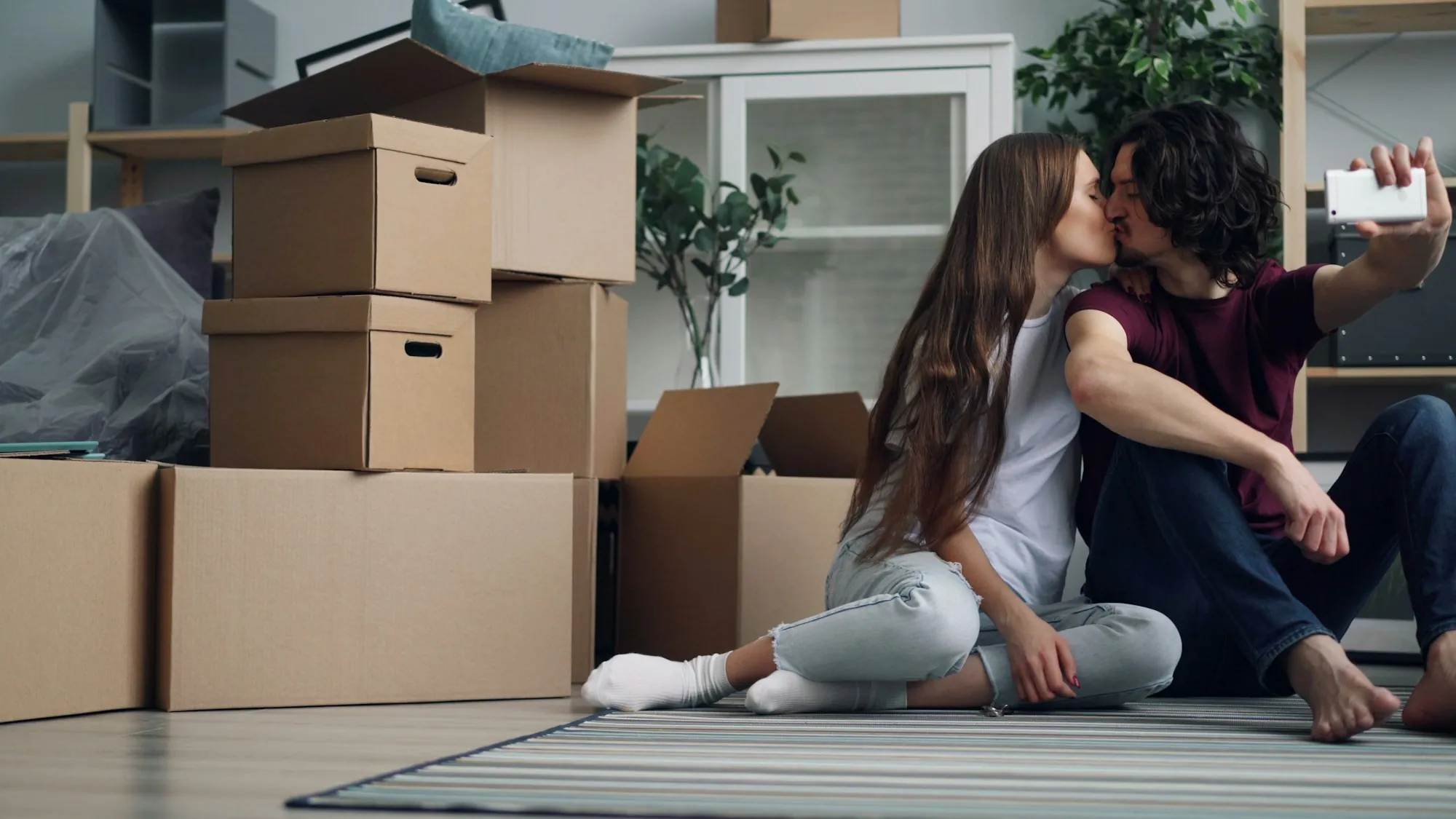 Couple sitting among moving boxes sharing a kiss